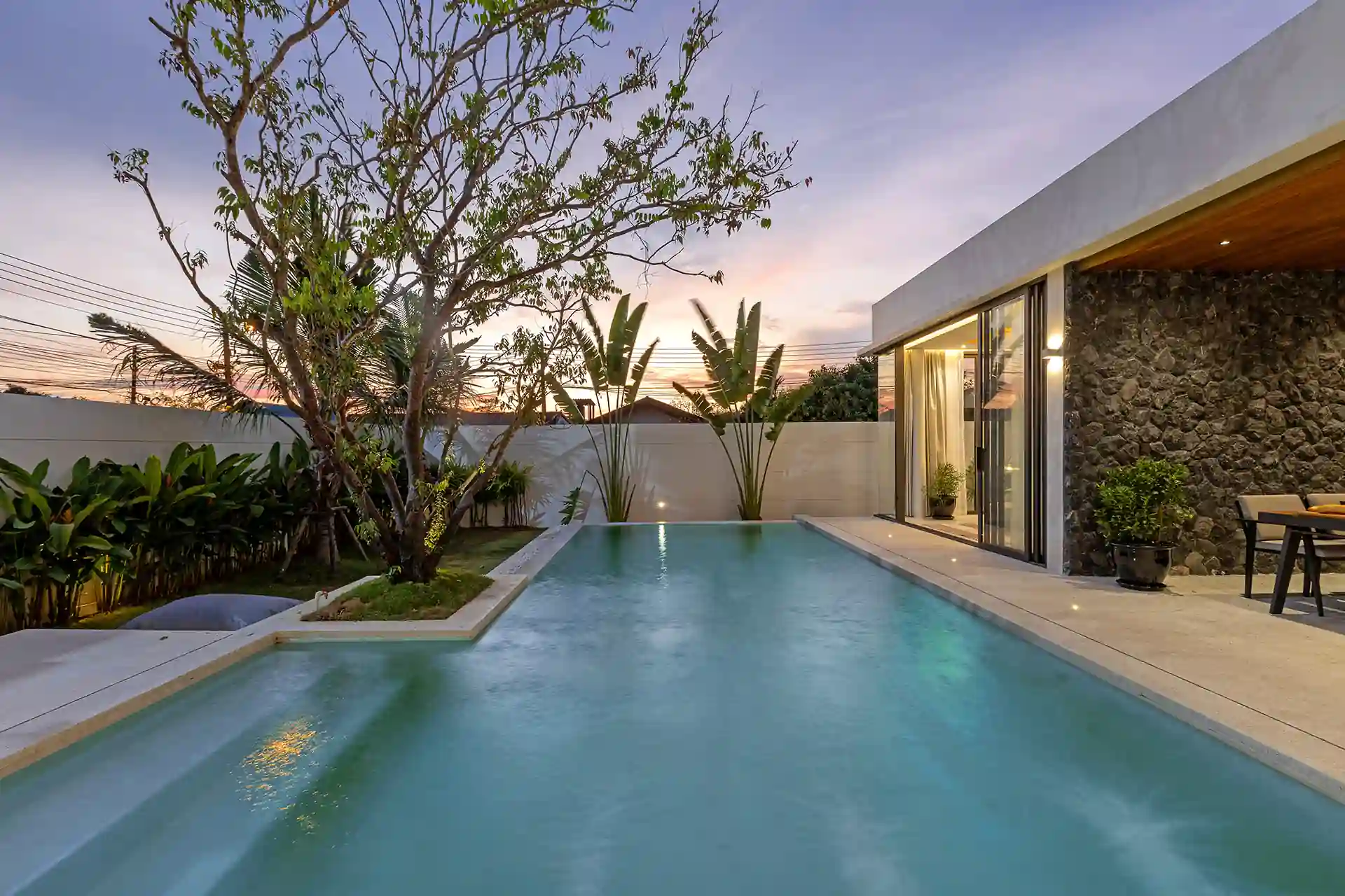 Mouana Cherng Talay sunset pool with stone wall and tropical foliage