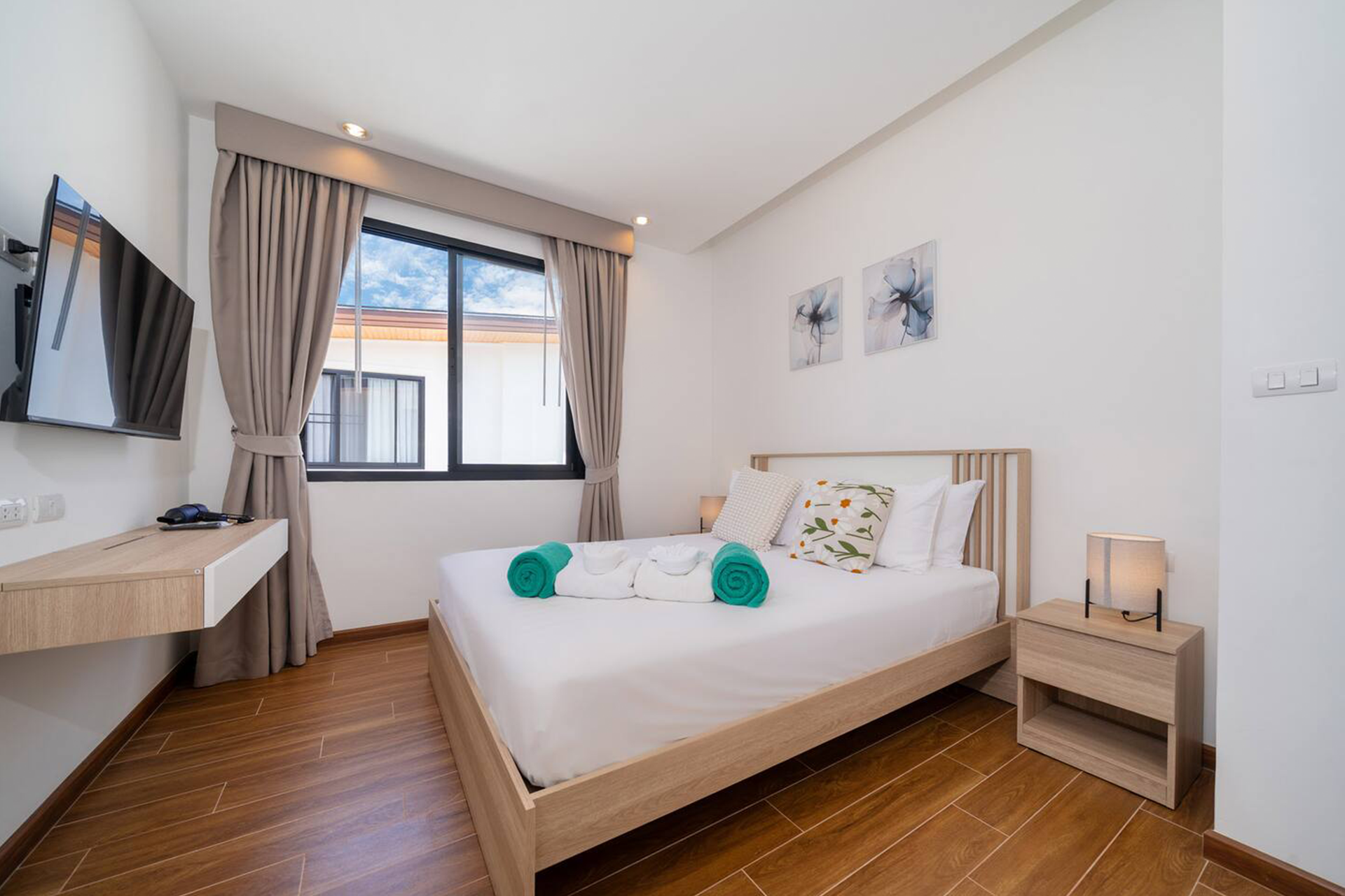 Goldena Twin Kamala guest bedroom with wall-mounted TV and curtains