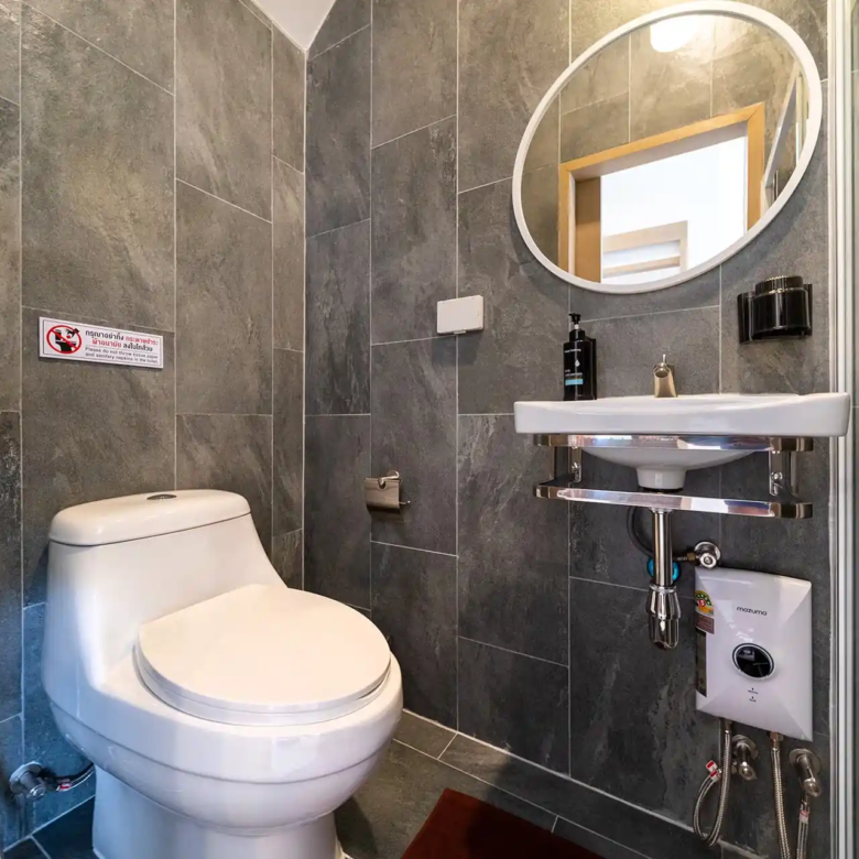 Goldena City Gems Kamala bathroom with toilet sink and dark tiles